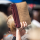 A supporter holds a bible into the air during a rally for County Clerk Kim Davis in front of the Carter County Detention Center on September 8, 2015 in Grayson, Kentucky. Image via Getty.